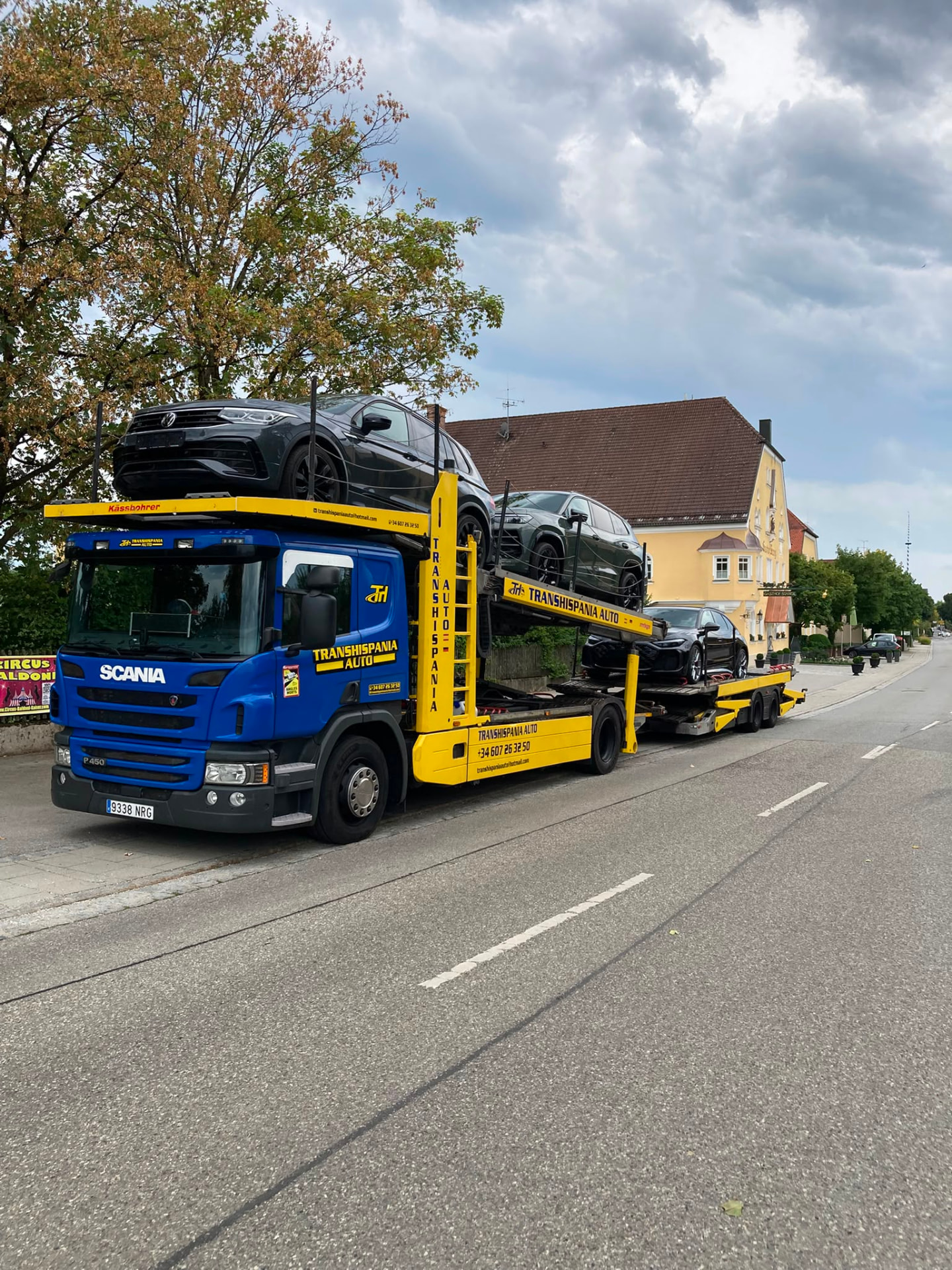 Camión portavehículos abierto transportando varios coches por una autopista europea