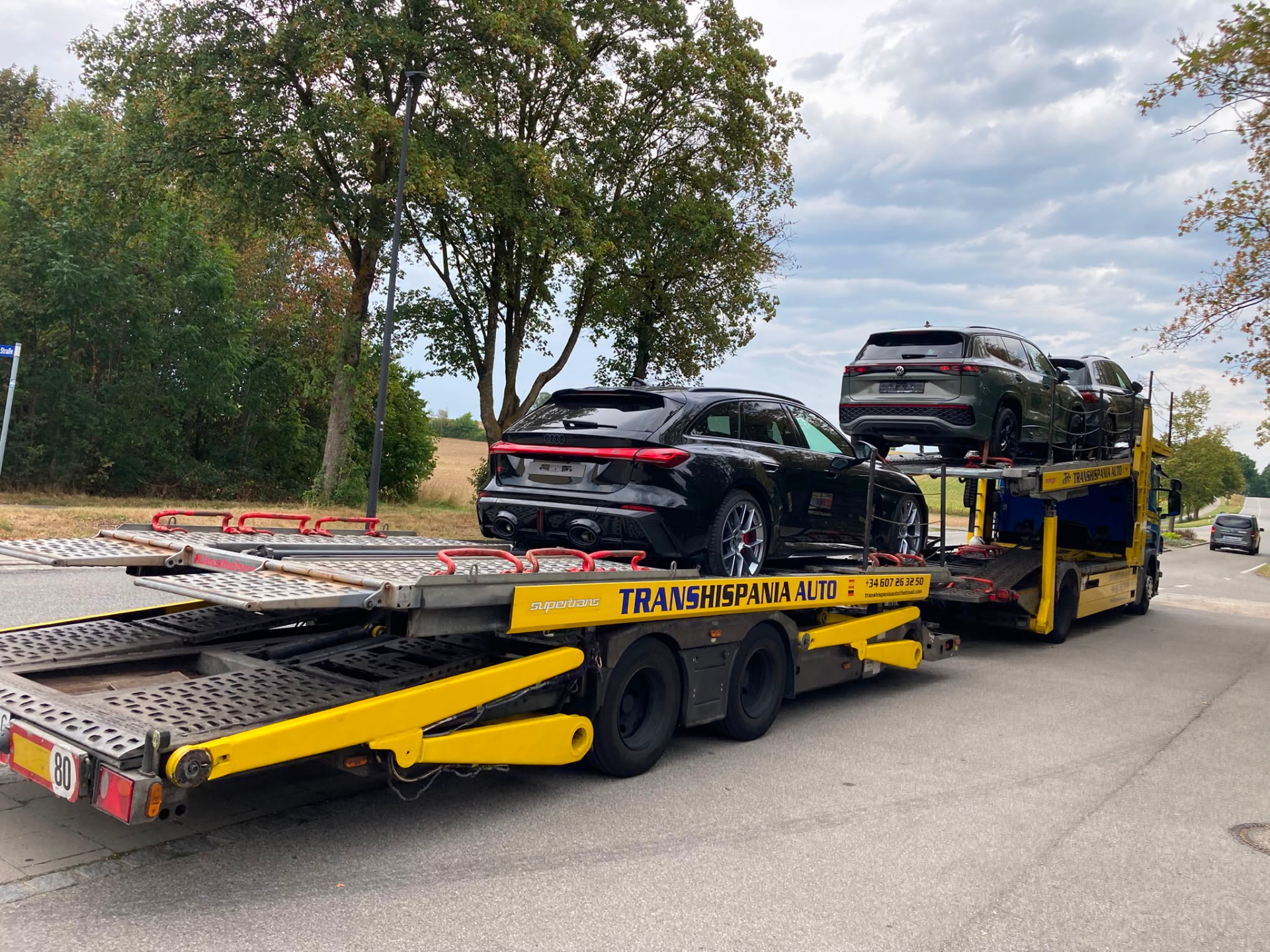Camión portavehículos abierto transportando varios coches por una autopista europea